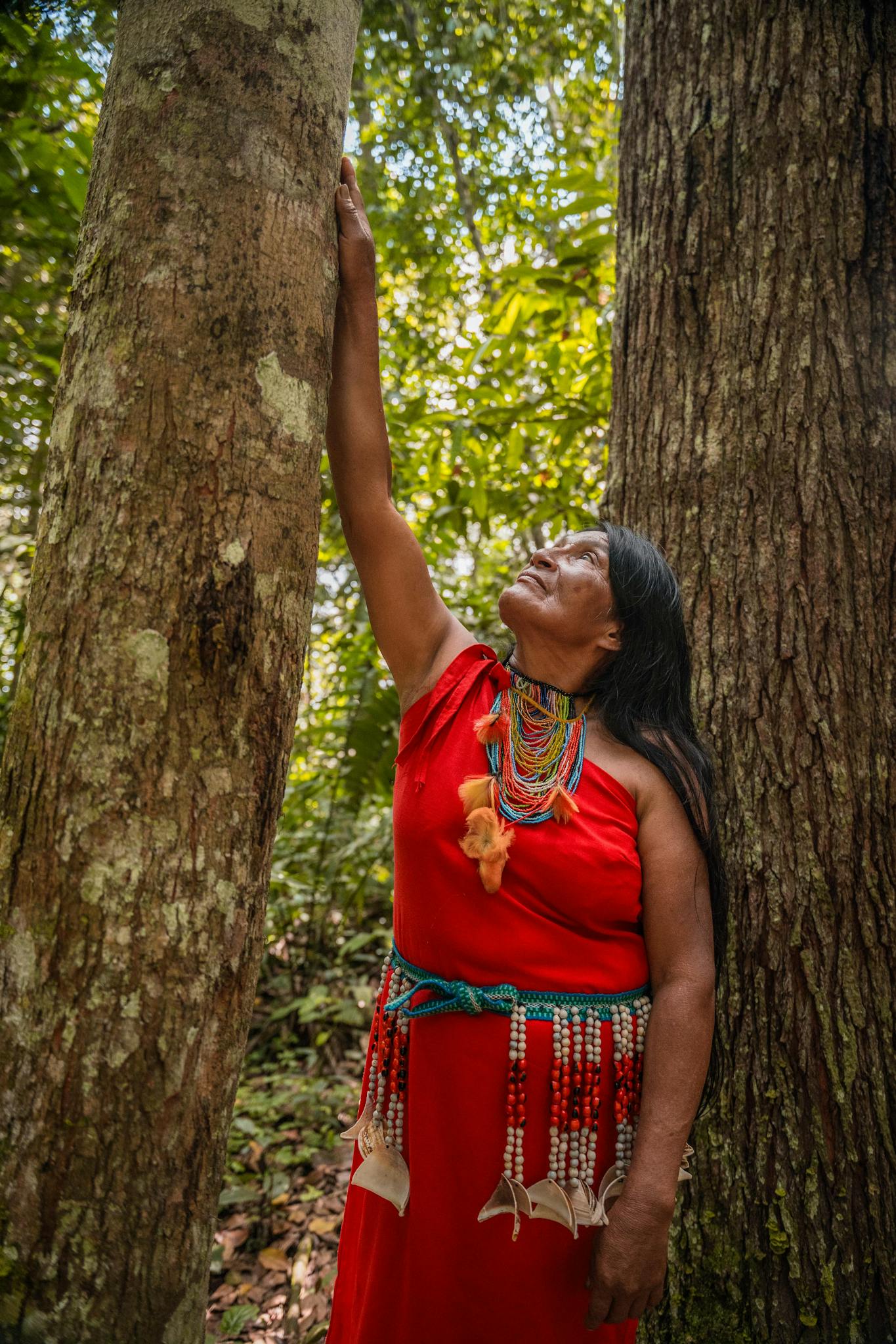 A woman in traditional attire stands among trees in San Martín, Peru, showcasing cultural beauty.
