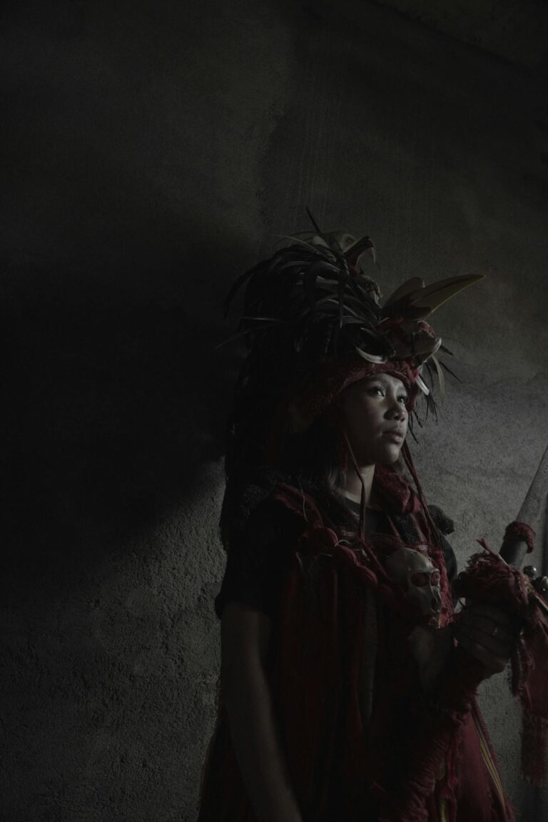 Portrait of a woman in traditional attire with a dramatic dark background, evoking cultural heritage.