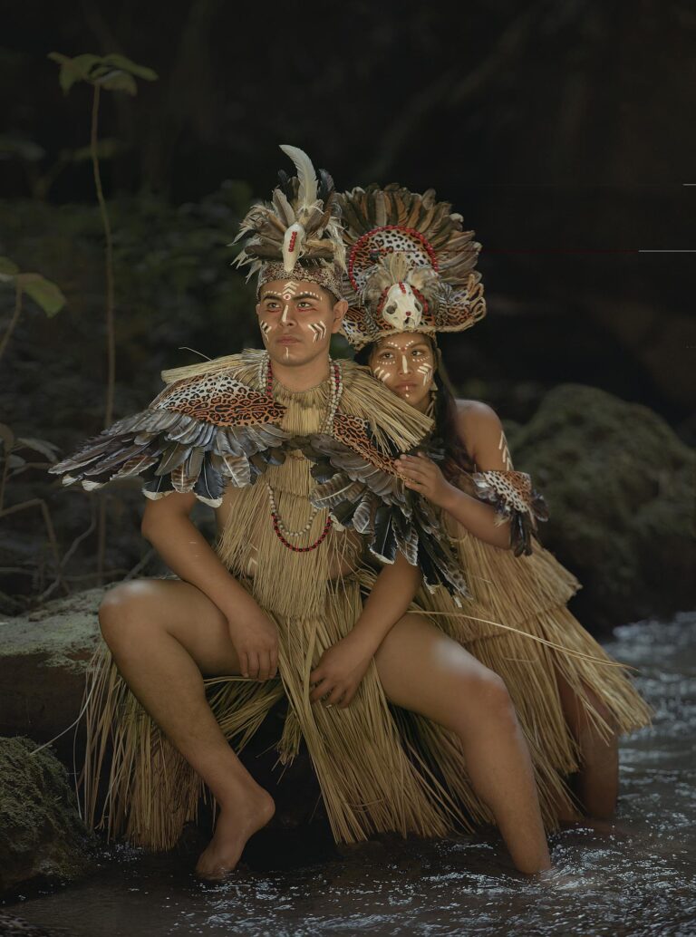 Two adults in traditional Peruvian tribal attire by a river in Tingo María, Peru's rainforest.